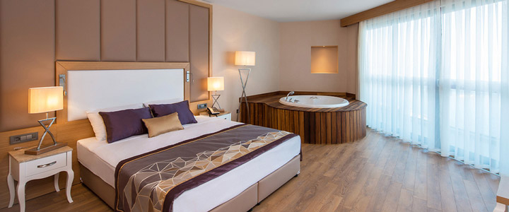 Ein modernes, lichtdurchflutetes Economy-Doppelzimmer öffnet sich zum Balkon. Im Raum steht ein Whirlpool als zentrales Element, ruhig eingebettet in klare, zeitgemäße Architektur.
